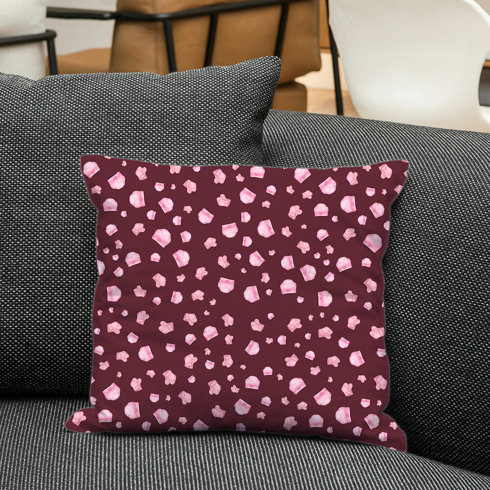 Dark brown pillow with soft pink baby essentials, styled on a grey sofa to create a cozy and sweet nursery-inspired look.