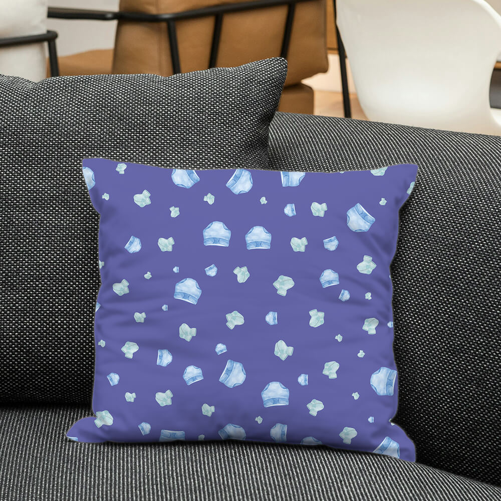 Very Peri pillow with baby diaper pattern placed on a dark couch for a cozy nursery-inspired decorative look.