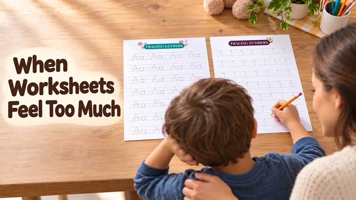 Young child feels overwhelmed by alphabet and number tracing worksheets as a parent offers gentle support at the table.